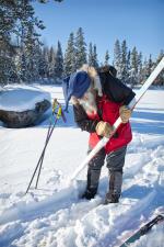 Dan scrapes ice from the skis. Slush under the snow is becoming a problem. When the slush hits the cold air above it freezes instantly.